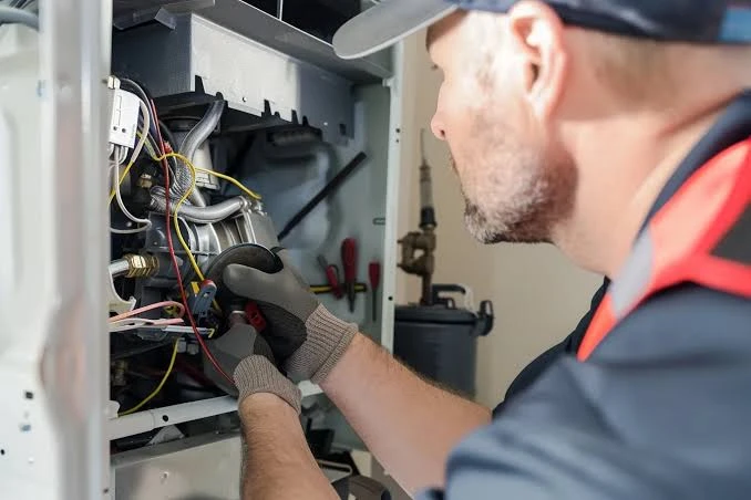 Illustrative technician checking wiring inside a furnace cabinet
